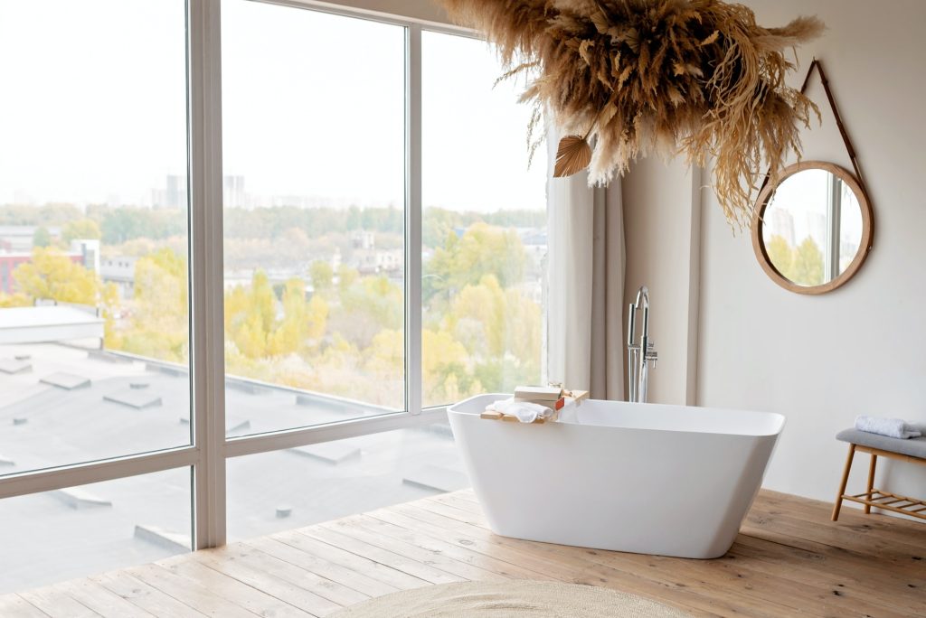 Comfortable bright bathroom with a boho-chic interior design, a free-standing white bath
