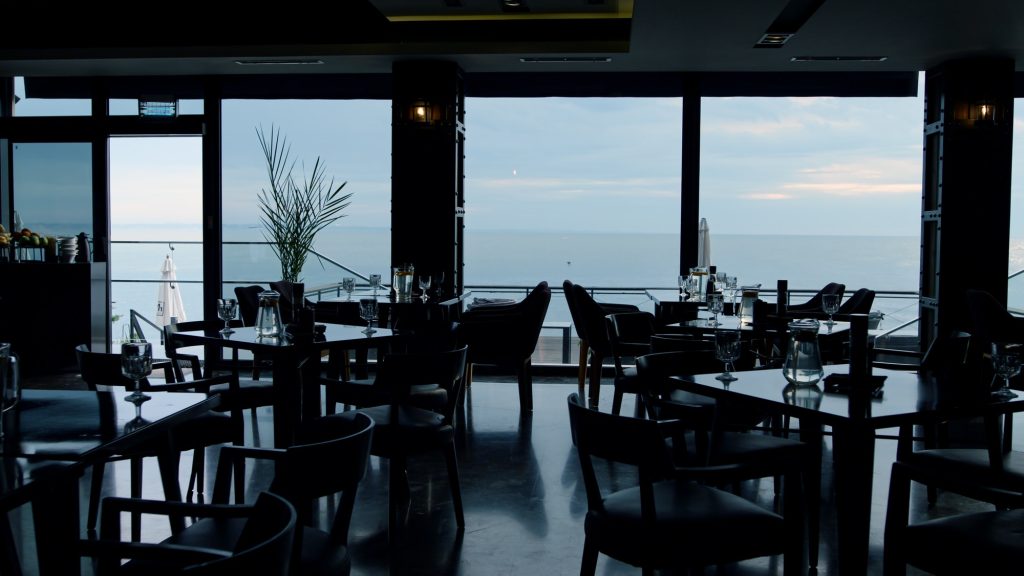 Dark interior in modern panoramic bar. Scenic ocean view in luxury lounge cafe