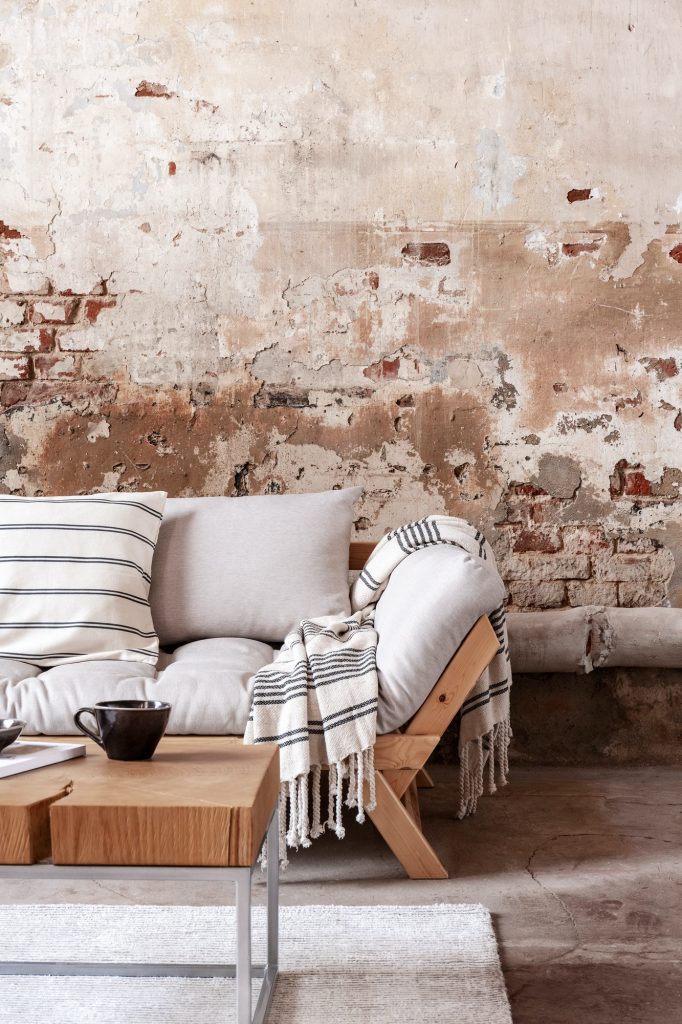 Wooden table in front of grey couch with blanket in wabi sabi li