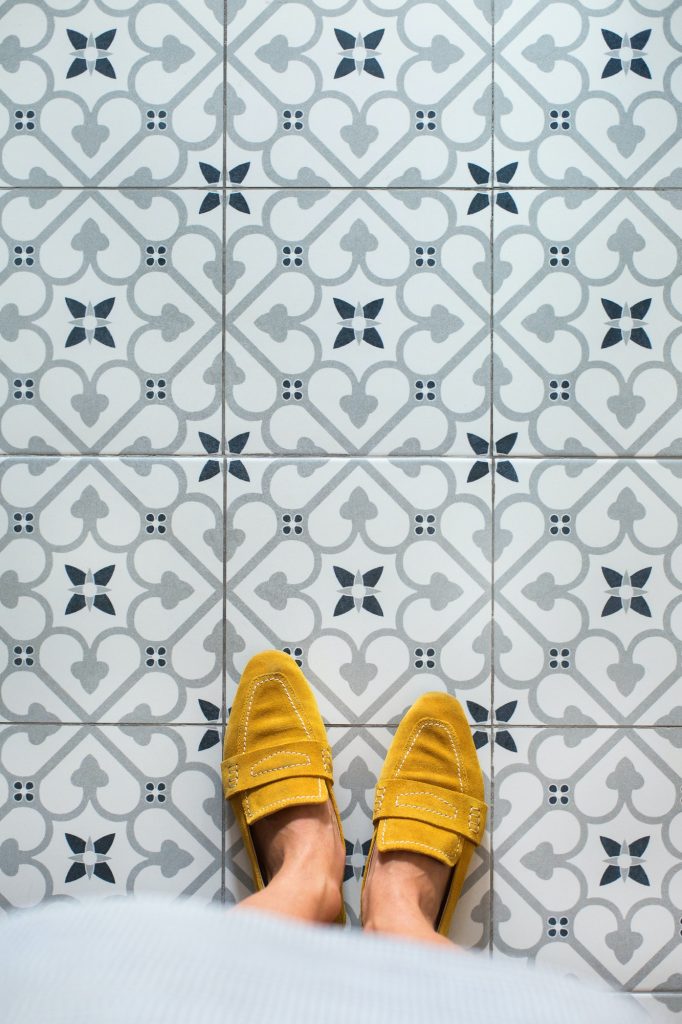 Selfie of female feet in yellow shoes on mosaic floor